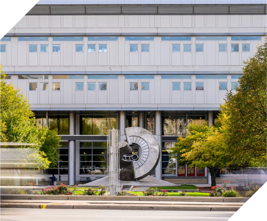 school building with trees and a large sculpture