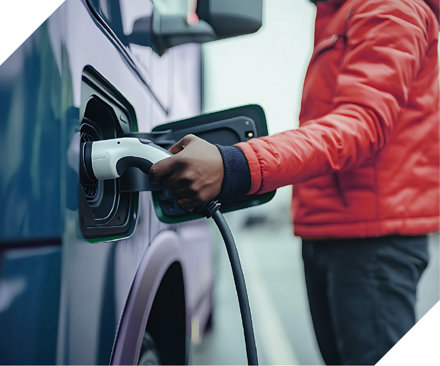 person holding an electric charging cord up to a semi truck cab